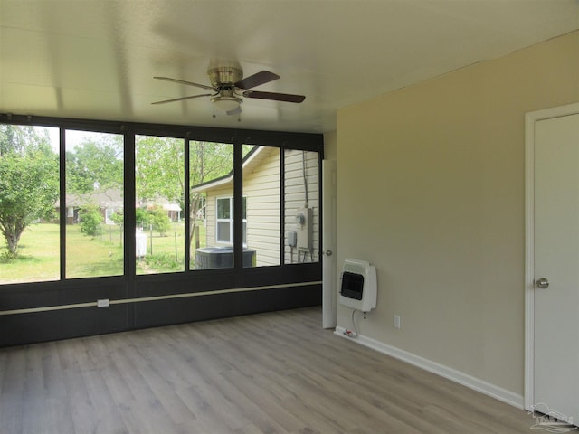 spare room with baseboards, a ceiling fan, wood finished floors, and heating unit