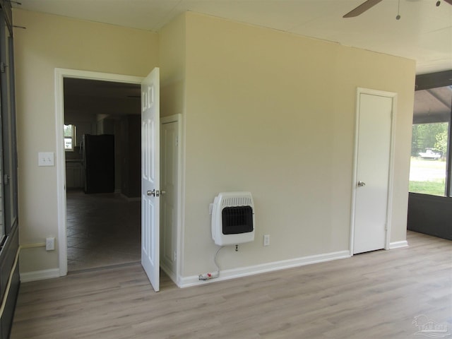 interior space featuring light wood-type flooring, heating unit, baseboards, and a ceiling fan