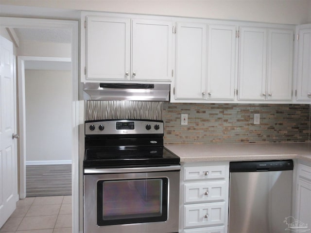 kitchen featuring under cabinet range hood, stainless steel appliances, light countertops, light tile patterned flooring, and white cabinetry