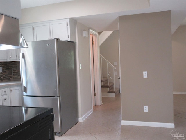 kitchen with white cabinets, freestanding refrigerator, backsplash, and light tile patterned floors
