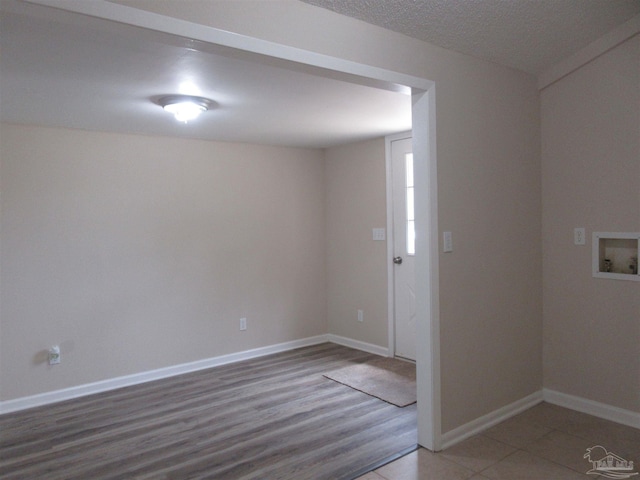 unfurnished room with baseboards, wood finished floors, and a textured ceiling