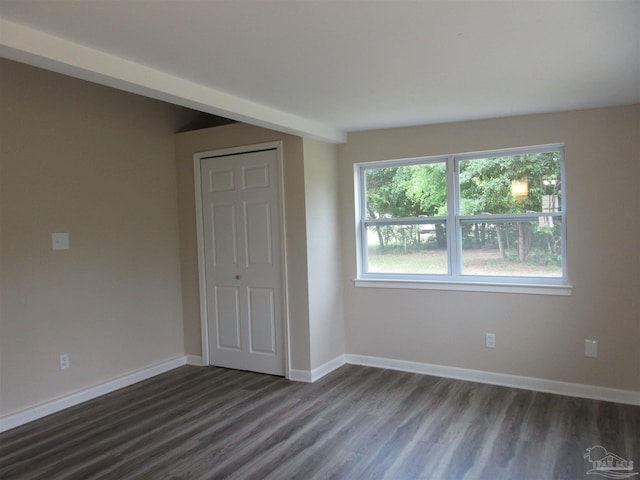 empty room with dark wood finished floors and baseboards