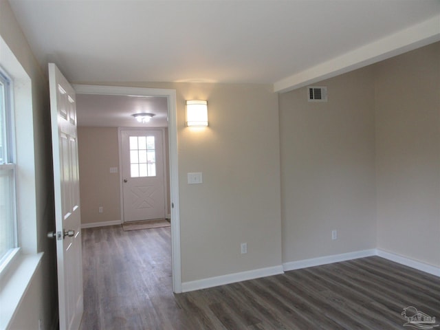unfurnished room featuring baseboards, dark wood-style flooring, and visible vents