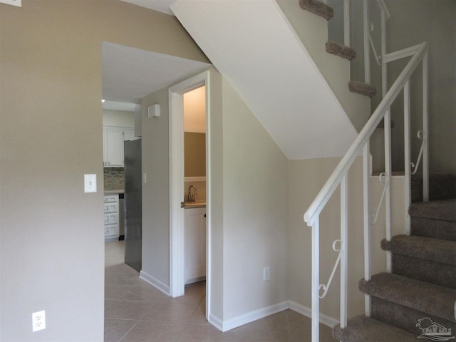 stairway with baseboards and tile patterned floors