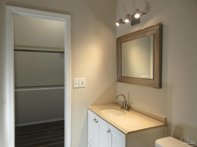 half bathroom featuring wood finished floors, vanity, and toilet
