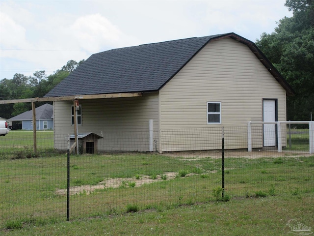 view of side of home with a lawn, fence, and roof with shingles