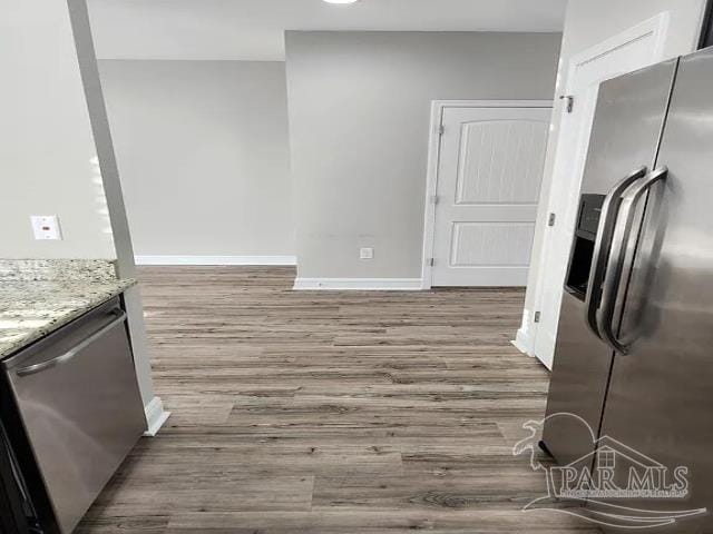 kitchen featuring stainless steel appliances, light stone countertops, and hardwood / wood-style floors