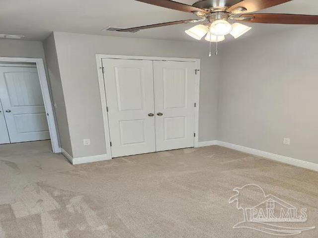 unfurnished bedroom featuring ceiling fan, light colored carpet, and a closet