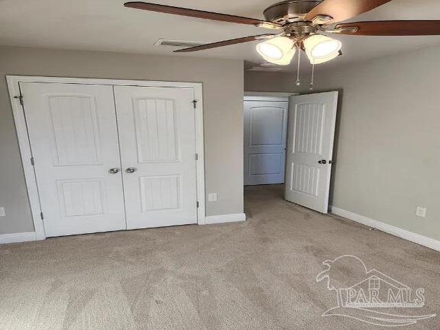 unfurnished bedroom with ceiling fan, light colored carpet, and a closet