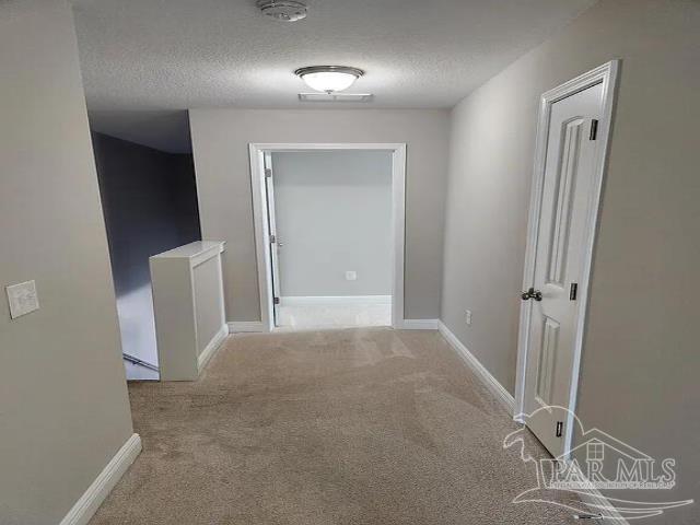 corridor featuring light colored carpet and a textured ceiling