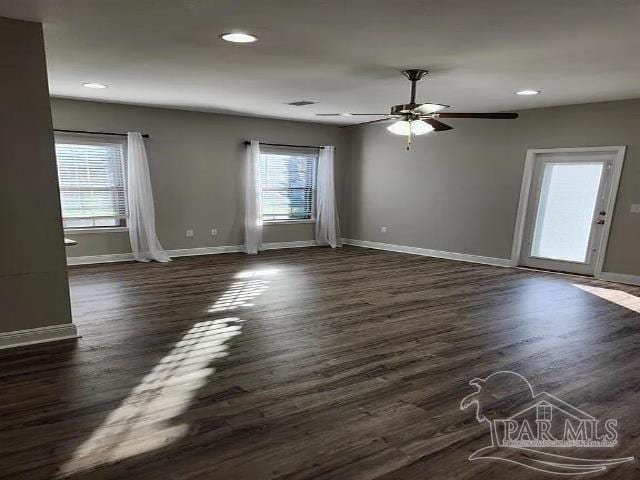 empty room featuring ceiling fan, a healthy amount of sunlight, and dark hardwood / wood-style floors