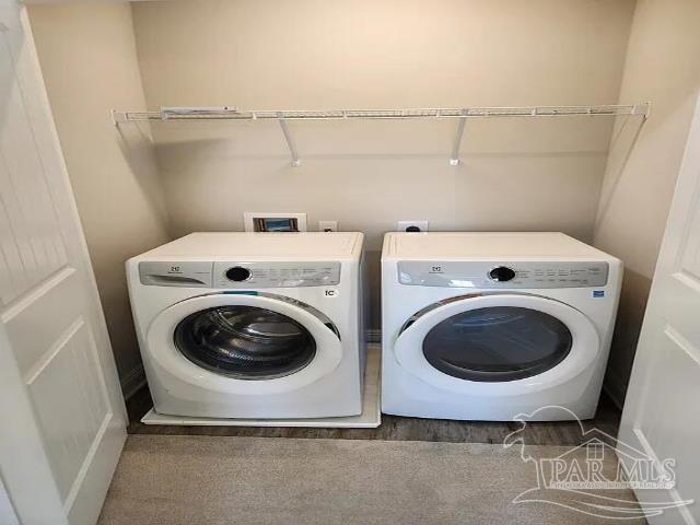 clothes washing area with washing machine and clothes dryer and dark hardwood / wood-style flooring