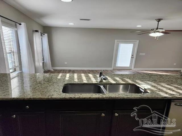 kitchen featuring light stone countertops, sink, and ceiling fan