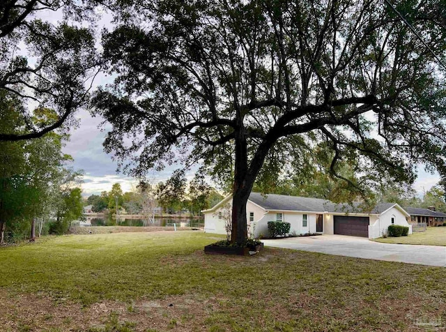 view of front of property with a garage, a water view, and a front lawn