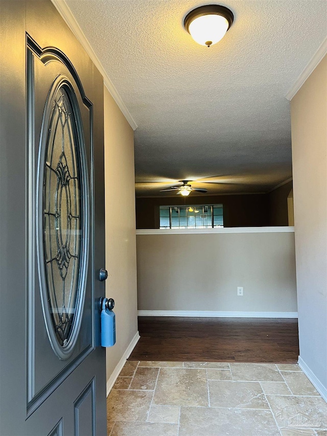 entrance foyer with a textured ceiling, ceiling fan, and crown molding