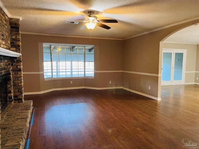 unfurnished living room featuring a brick fireplace, a textured ceiling, ornamental molding, and hardwood / wood-style flooring