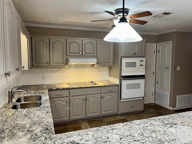 kitchen with sink, a textured ceiling, light stone counters, white appliances, and ceiling fan