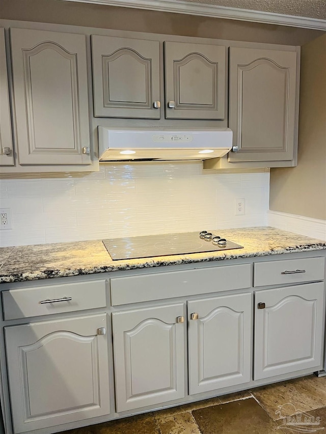 kitchen featuring light stone counters, electric stovetop, and decorative backsplash