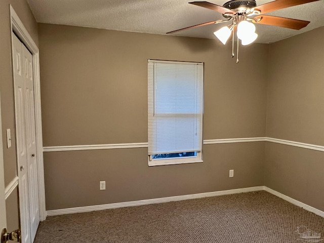 empty room with a textured ceiling, carpet floors, and ceiling fan