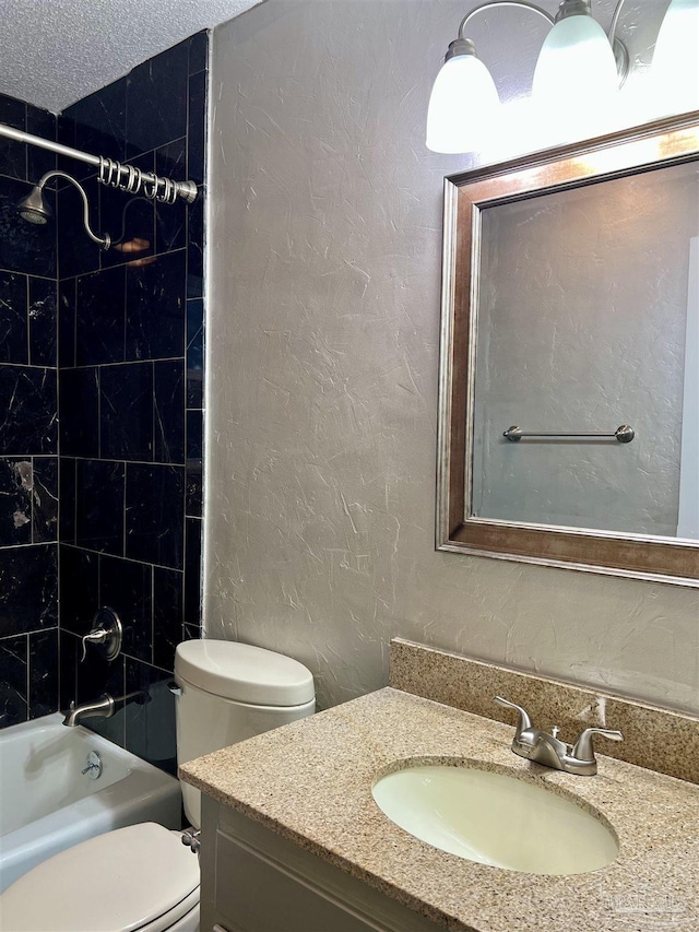 full bathroom featuring toilet, a textured ceiling, tiled shower / bath, and vanity