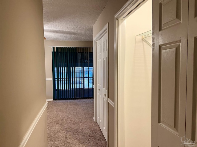 hall with a textured ceiling and light carpet