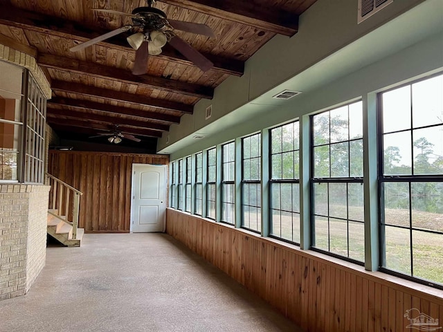 unfurnished sunroom with wood ceiling, a healthy amount of sunlight, and beamed ceiling