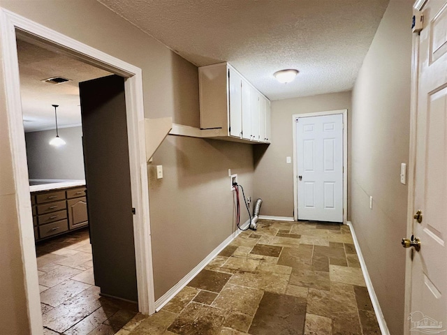 washroom with a textured ceiling, hookup for a washing machine, and cabinets