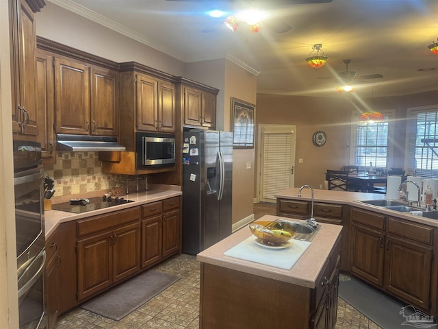 kitchen featuring a kitchen island, appliances with stainless steel finishes, sink, decorative backsplash, and crown molding