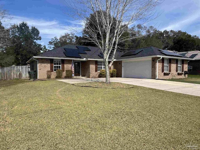 ranch-style house featuring an attached garage, fence, driveway, roof mounted solar panels, and a front yard