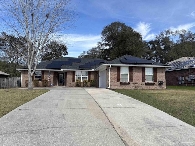 ranch-style house with solar panels, concrete driveway, an attached garage, a front lawn, and brick siding