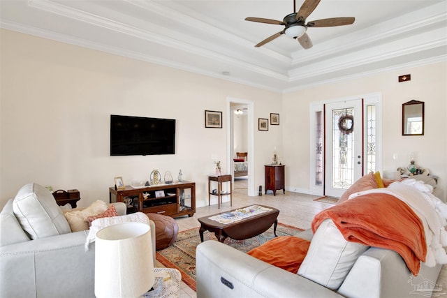 living room with a raised ceiling, ceiling fan, and crown molding