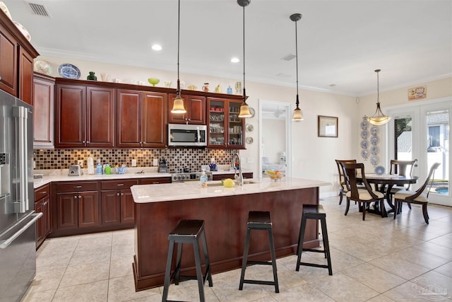 kitchen featuring sink, hanging light fixtures, stainless steel appliances, a kitchen bar, and a center island with sink