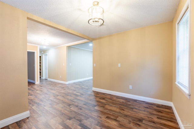 empty room with a textured ceiling, crown molding, and dark wood-type flooring