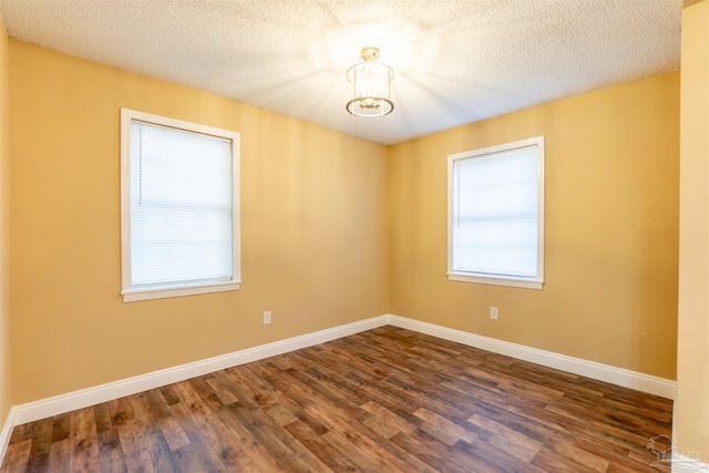 spare room with a textured ceiling and dark hardwood / wood-style flooring