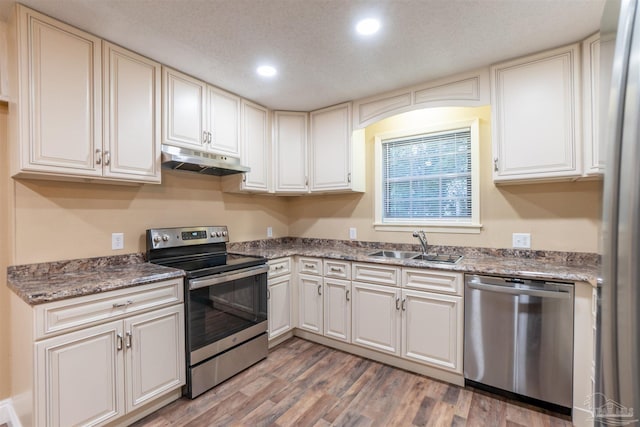 kitchen with white cabinetry, appliances with stainless steel finishes, hardwood / wood-style flooring, and sink