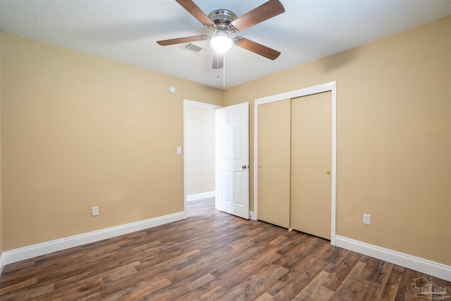 unfurnished bedroom with ceiling fan, a textured ceiling, a closet, and dark hardwood / wood-style floors