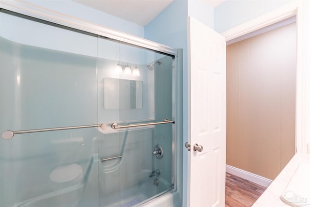 bathroom featuring enclosed tub / shower combo, a textured ceiling, toilet, and hardwood / wood-style flooring