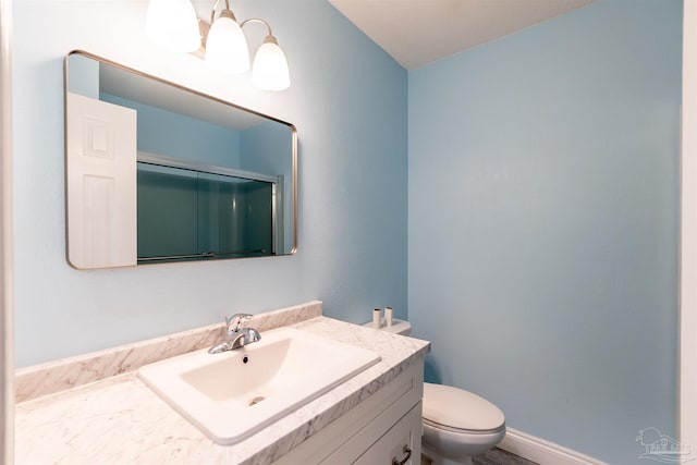 bathroom featuring vanity, a shower with shower door, and toilet