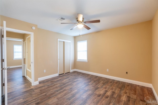 unfurnished bedroom featuring multiple windows, ceiling fan, and dark wood-type flooring