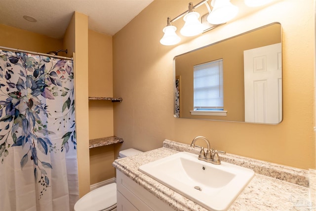 bathroom with walk in shower, vanity, toilet, and a textured ceiling