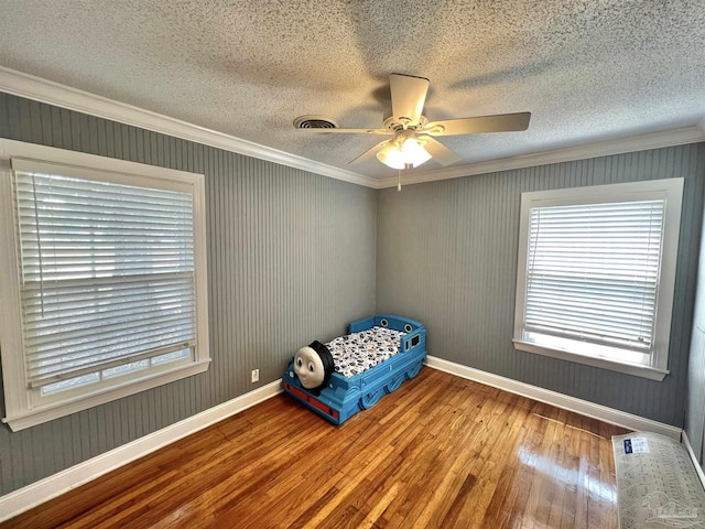 704 E Horner St, Atmore, AL 36502 - unfurnished bedroom with wood-type flooring, baseboards, a textured ceiling, crown molding, and a ceiling fan