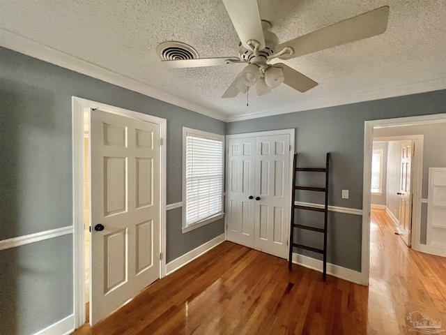704 E Horner St, Atmore, AL 36502 - unfurnished bedroom with wood finished floors, a textured ceiling, crown molding, a closet, and baseboards