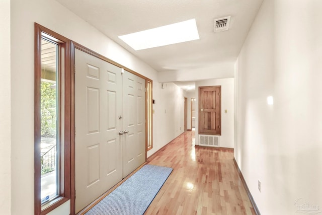 foyer entrance featuring a skylight and light hardwood / wood-style flooring