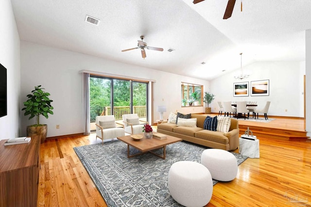 living room with ceiling fan, hardwood / wood-style flooring, vaulted ceiling, and a textured ceiling