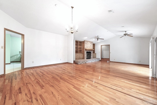 unfurnished living room with a brick fireplace, ceiling fan with notable chandelier, and light wood-type flooring