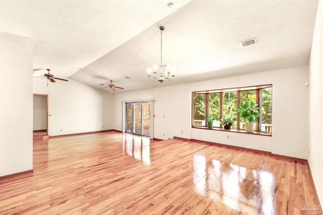 spare room with vaulted ceiling, a textured ceiling, ceiling fan with notable chandelier, and light hardwood / wood-style floors