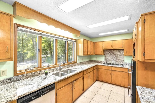 kitchen with appliances with stainless steel finishes, light stone countertops, light tile patterned floors, a textured ceiling, and sink