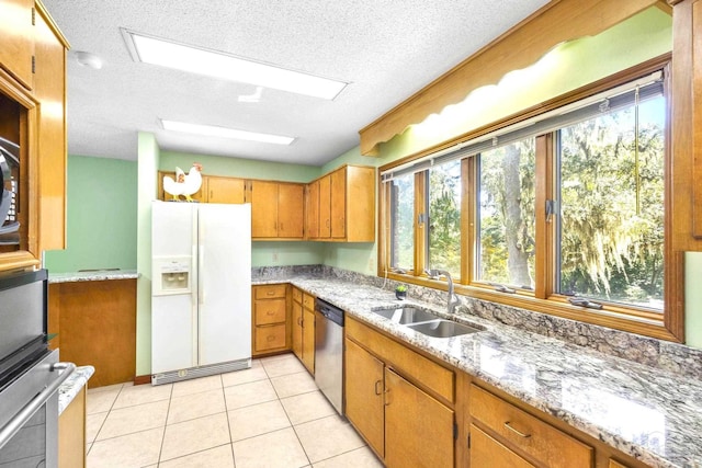 kitchen featuring white fridge with ice dispenser, a textured ceiling, sink, light tile patterned floors, and stainless steel dishwasher