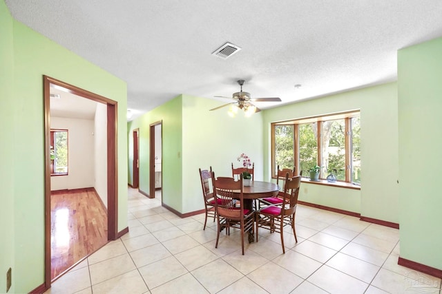 dining area with a textured ceiling, light wood-type flooring, and ceiling fan