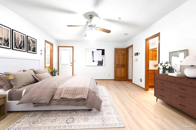 bedroom featuring ceiling fan, a textured ceiling, light wood-type flooring, and connected bathroom